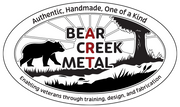 Bear Creek Metal Art LOGO featuring a bear, river, grass and tree  