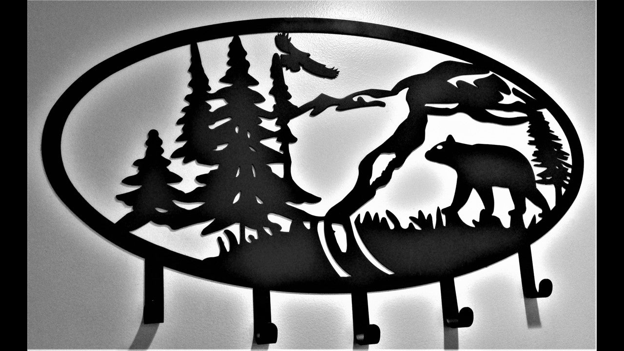 Custom black metal coat rack with Bear, Eagle, Mountain's, and Pine Tree's with 5 hooks. 36 inches wide by 21 inches high. Priced at 180.00 dollars.  SKU number CB18X36 