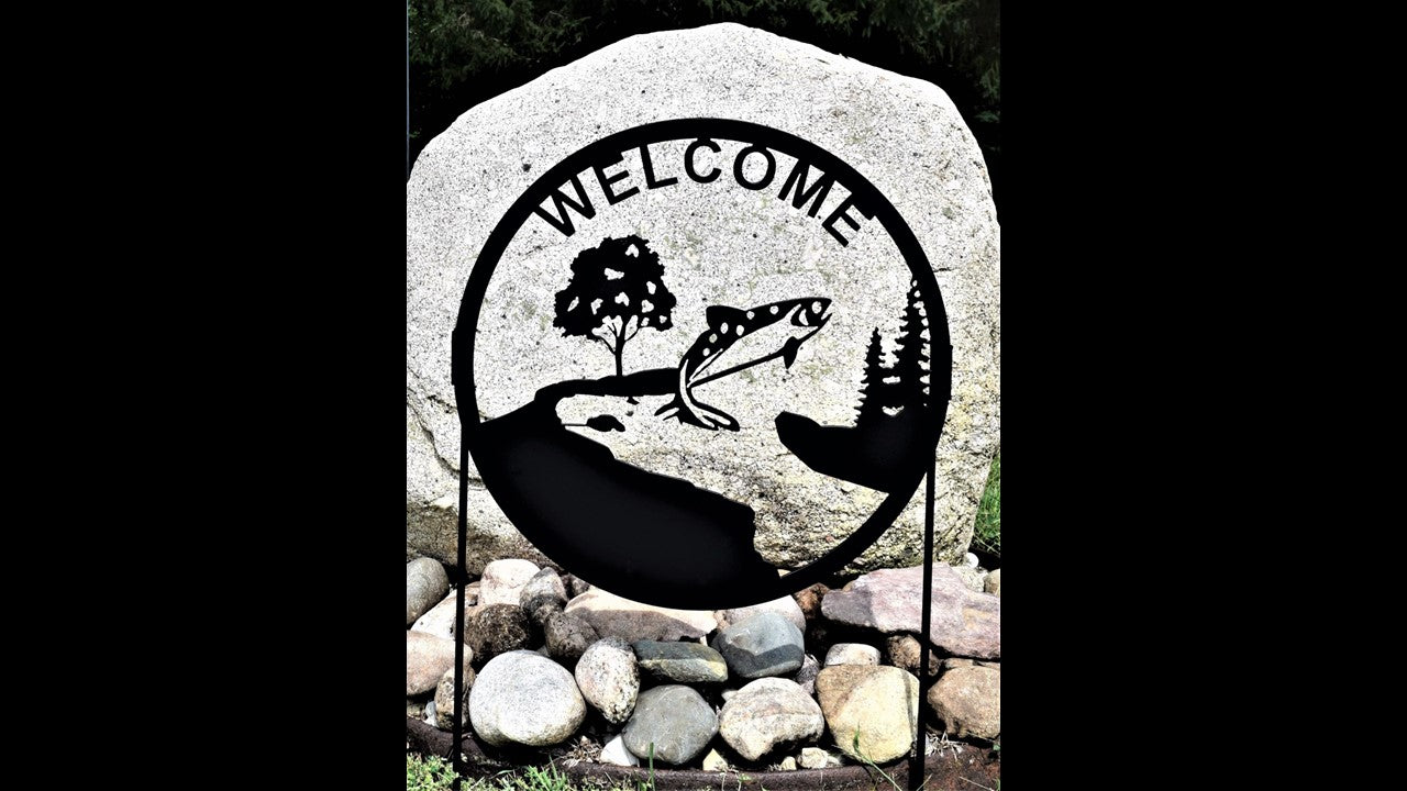 black metal custom yard welcome silhouette featuring a fish jumping out of water with trees and wrapped in a circle. Sign stakes are included. Priced at 60 dollars SKU number YWF18