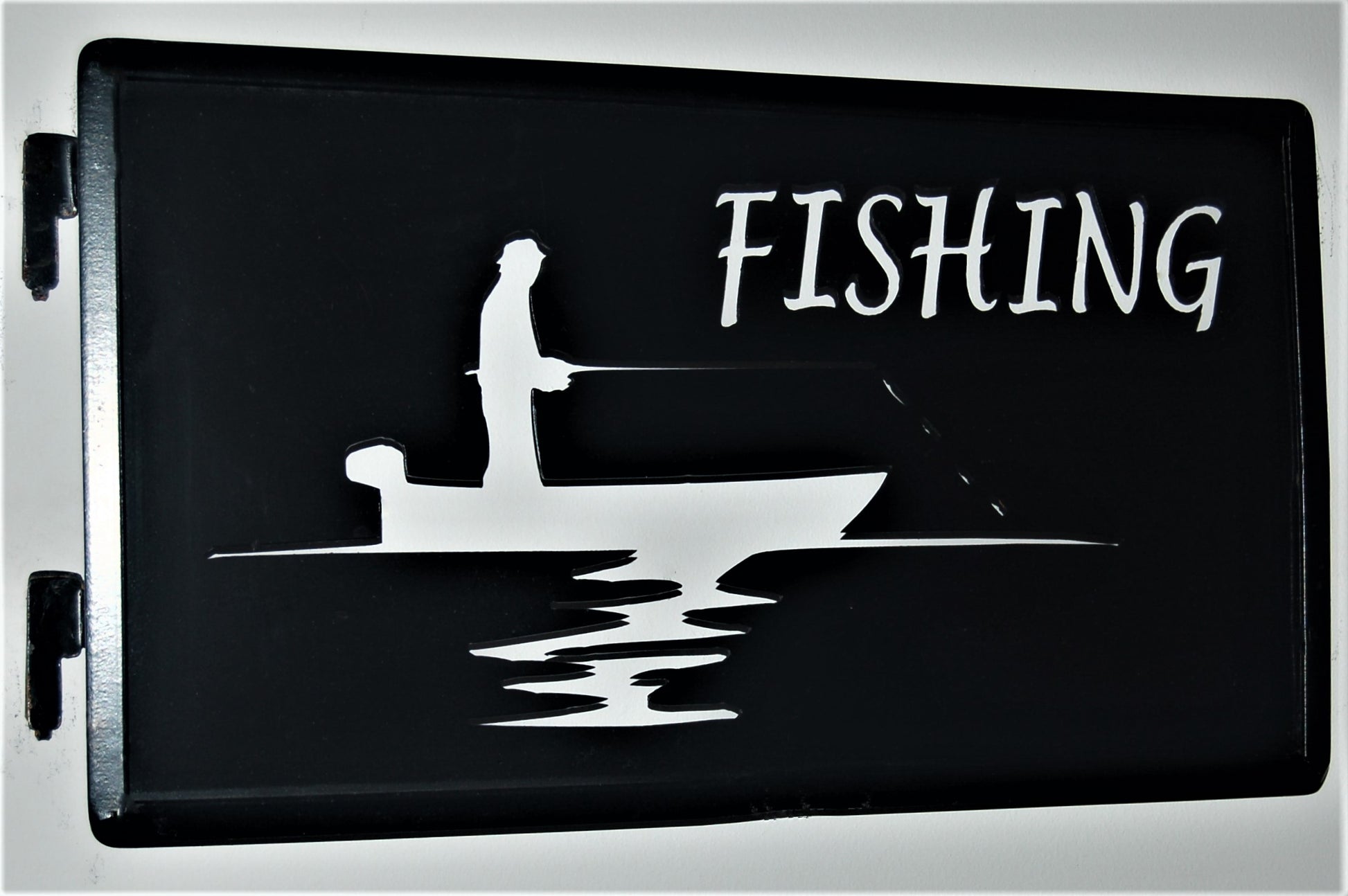 black metal Fishing inspiring panel featuring a fisherman, boat and pole in the water 