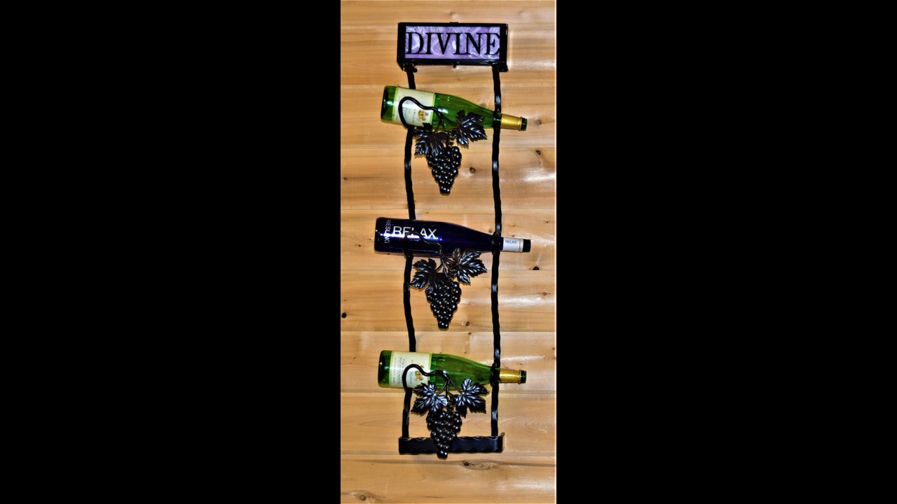 Custom black metal wine tree with grapes and vines holding 3 bottles. Featuring the word divine up top with purple backing behind the wording. 