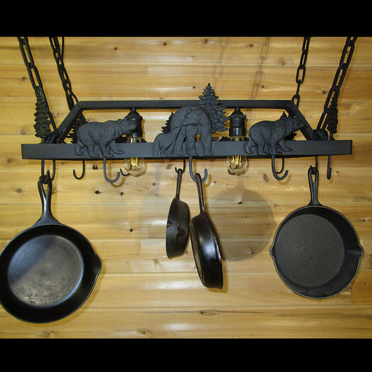 Black metal decorative hanging pot rack with dimensional bear and pine tree designs and lights set in the middle of the rack.